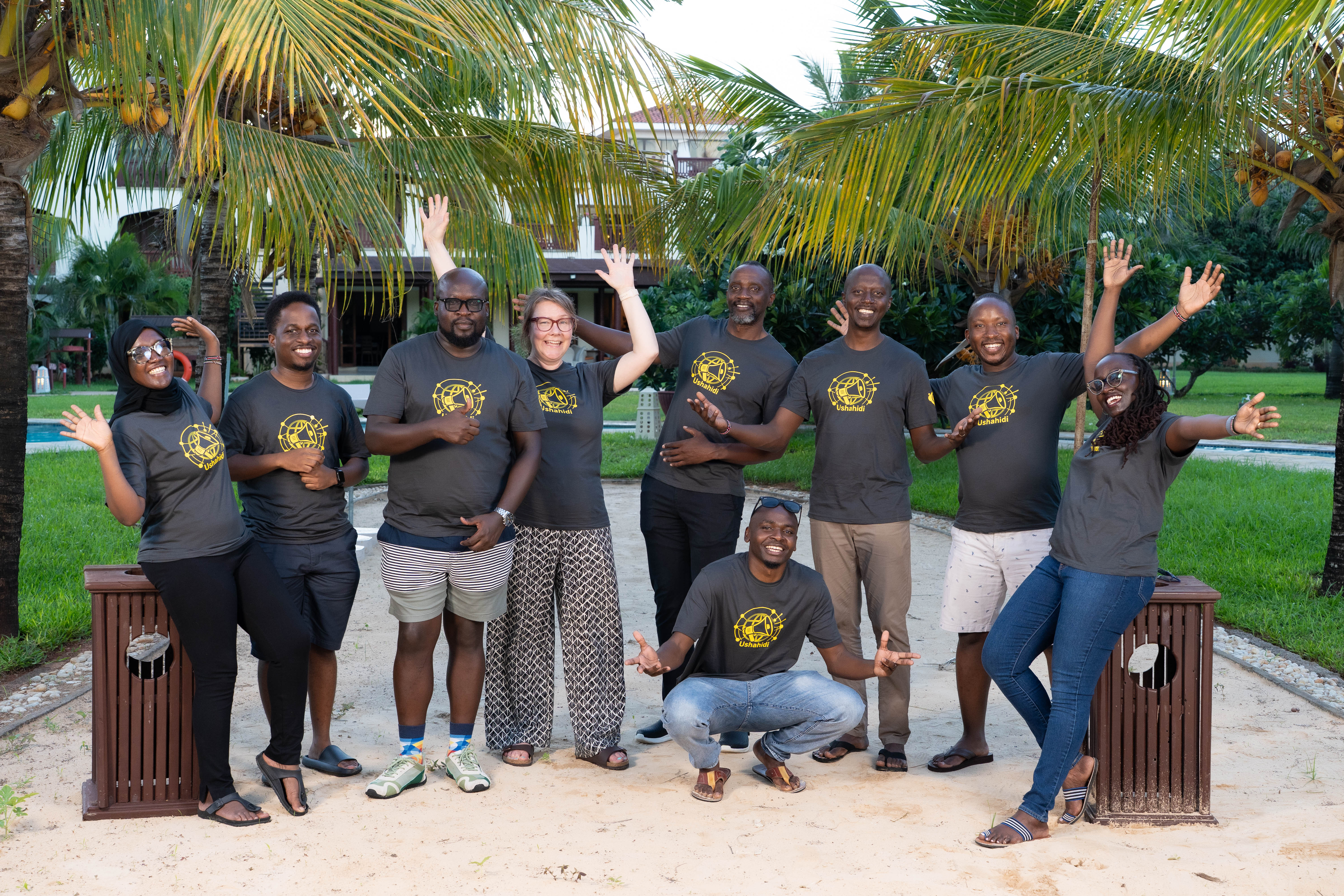 The Ushahidi team posing for a photo on a lawn in front of the ocean