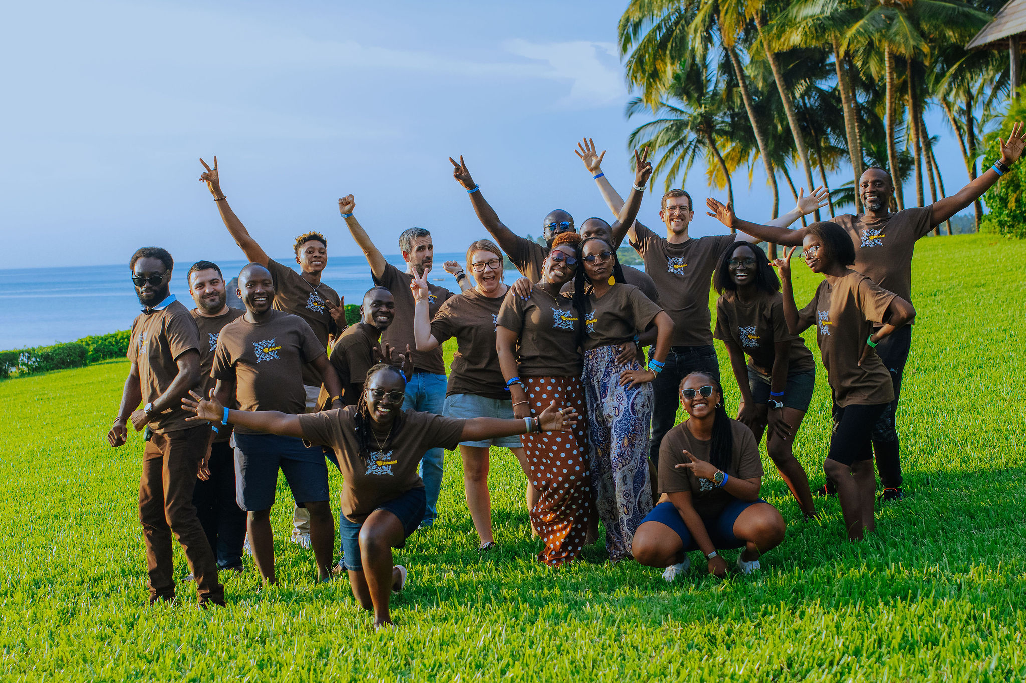 The Ushahidi team posing for a photo on a lawn in front of the ocean